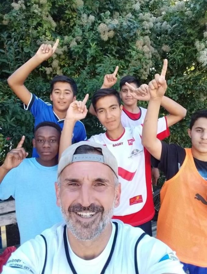 Ein Fußballtrainer steht vor einer Gruppe von jugendlichen Fußballspielern