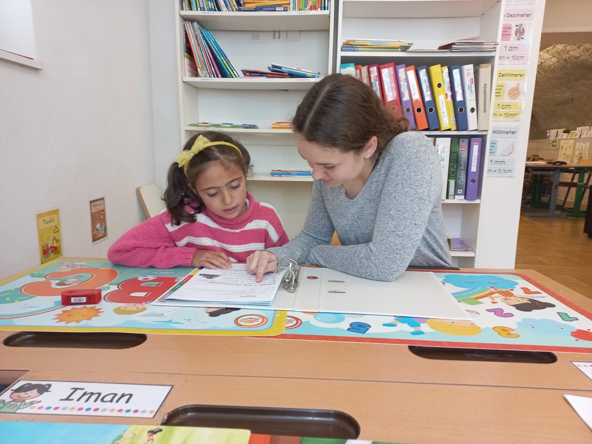 Ein kleines Mädchen sitzt gemeinsam mit einer Pädagogin an einer Schulaufgabe